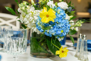 Vase of blue and white hydrangeas with bright yellow flowers